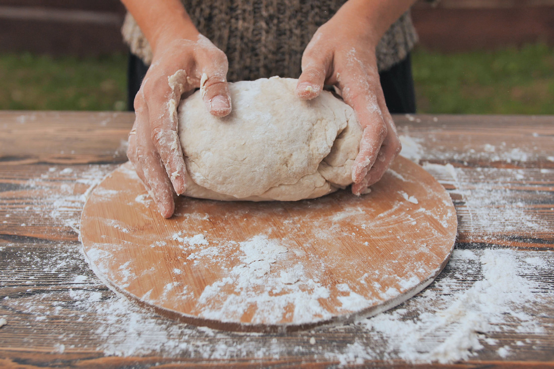 Hands shaping dough into loaf.